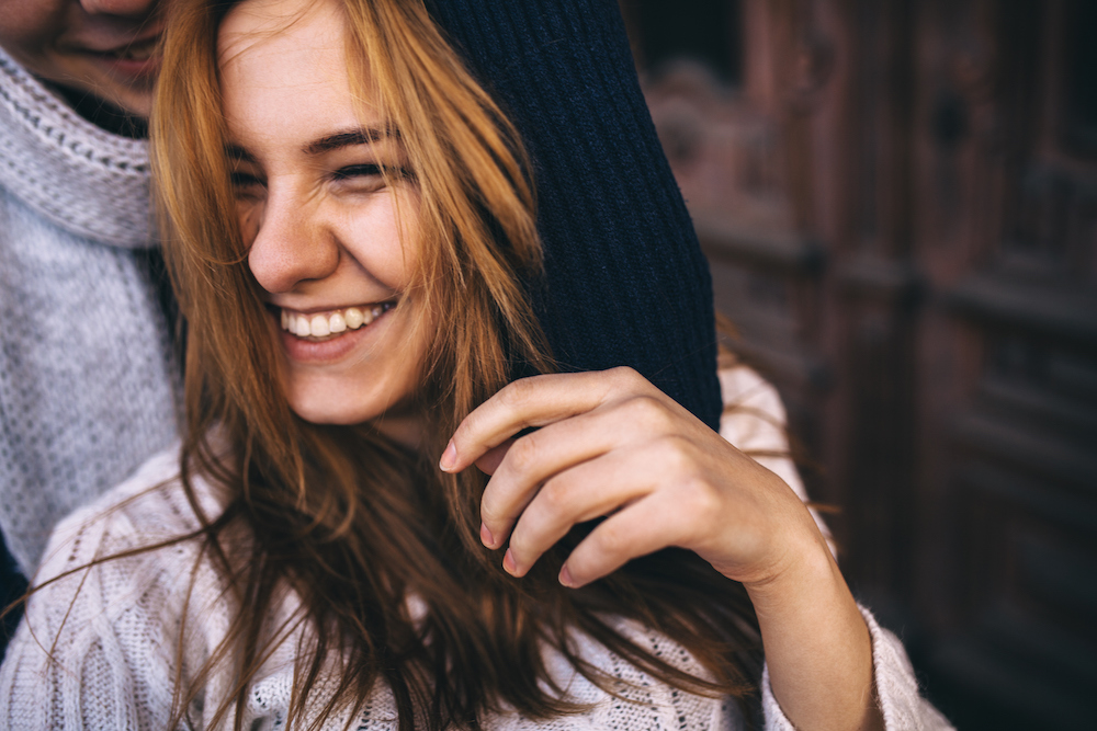Girl smiling being hugged by friend