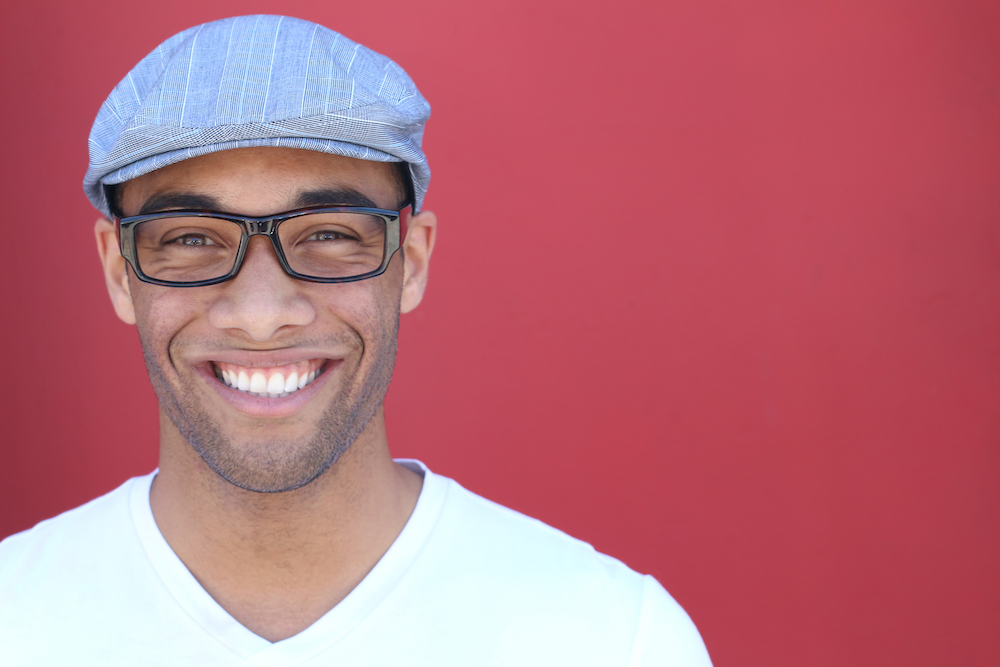 Man smiling in corner with hat